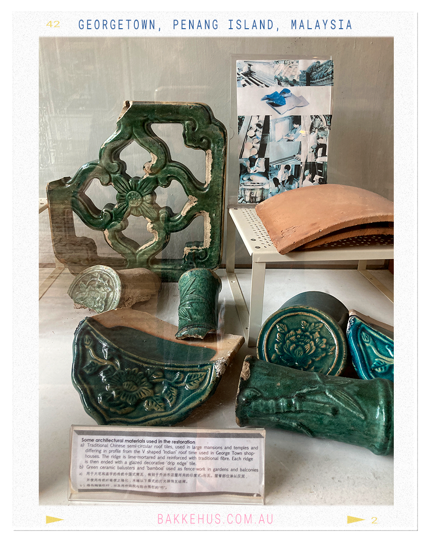 Display of traditional Chinese ceramic architectural fragments used in the restoration of George Town heritage buildings, including green-glazed roof tiles and decorative balusters, photographed at the Blue Mansion in Penang, Malaysia. © Heidi Isaksen-Loxton for bakkehus.com