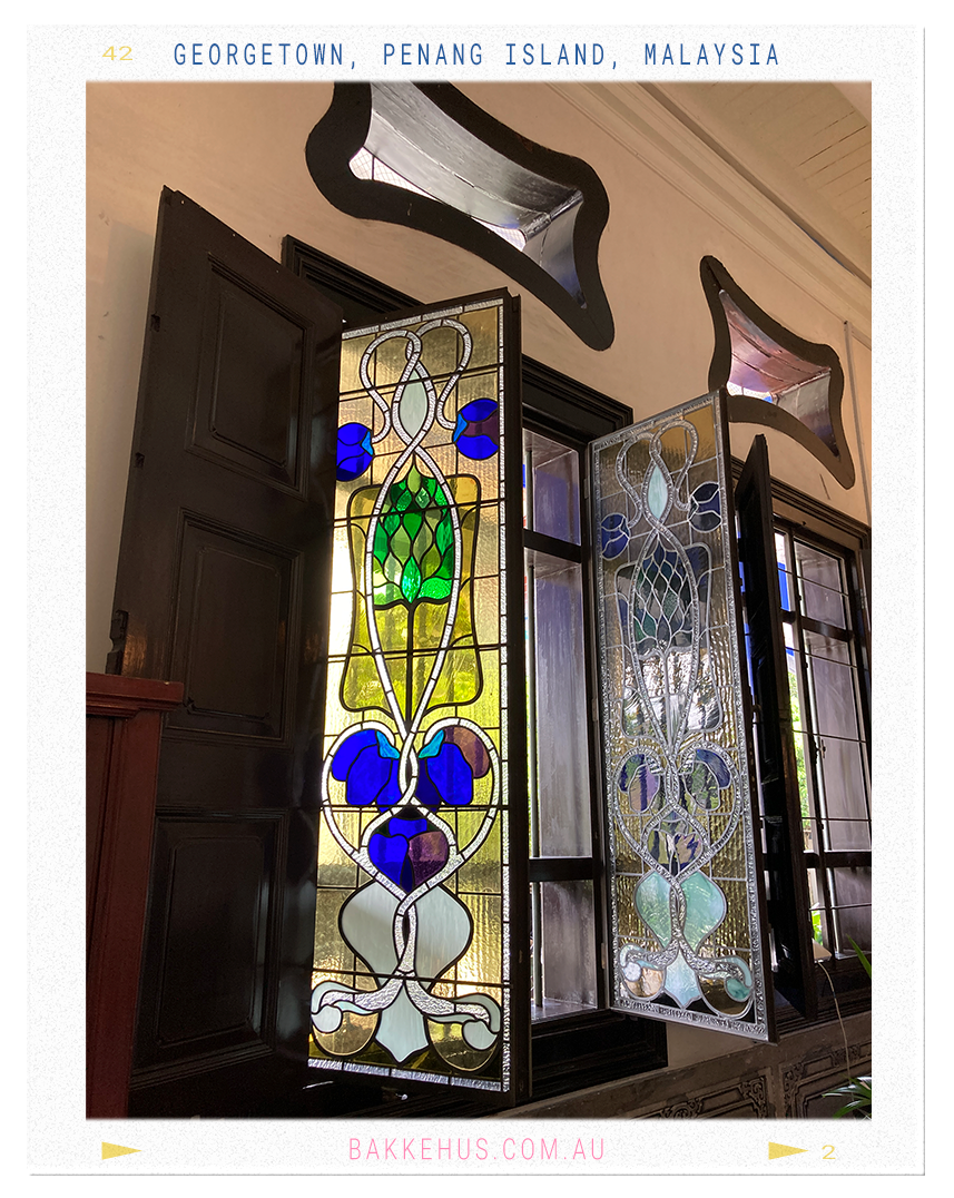 Close-up of vibrant Art Nouveau stained glass windows at the Blue Mansion in George Town, Penang, Malaysia, featuring floral-inspired motifs in green, blue, and lavender tones—highlighting the mansion’s East-meets-West architectural style. © Heidi Isaksen-Loxton for bakkehus.com