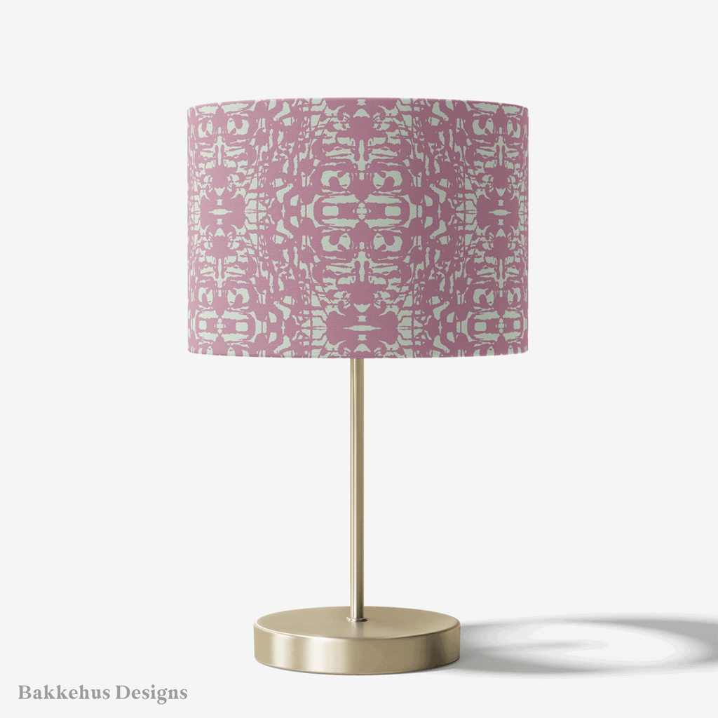 Table lamp with a brass stand and a round drum shade covered in the Abstract Inked Lace pattern in pale sage green and dusty mauve.