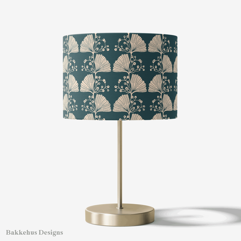 Table lamp with a brass stand and a round drum shade covered in the Art Nouveau Ginkgo Sprig pattern, with cream ginkgo leaves on deep teal.