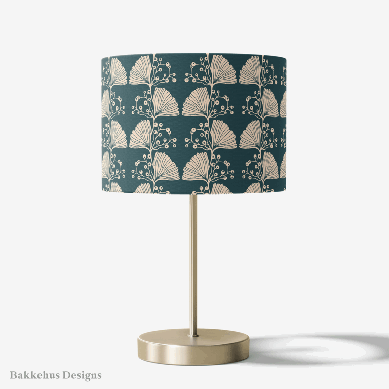 Table lamp with a brass stand and a round drum shade covered in the Art Nouveau Ginkgo Sprig pattern, with cream ginkgo leaves on deep teal.
