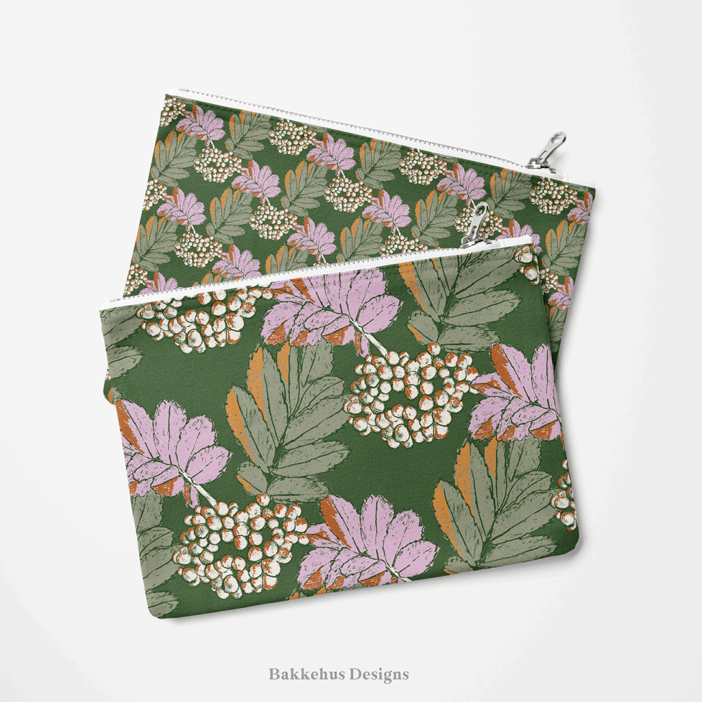 Two zip pouches made from Bramble & Berry Botanical fabric, one lying on the other, printed with lilac and cream berry clusters and leaves on forest green.