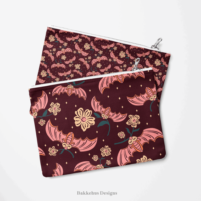 Two zip pouches made from Cute Flower Bats fabric, one lying on the other, printed with pink bats and cream flowers on dark plum.