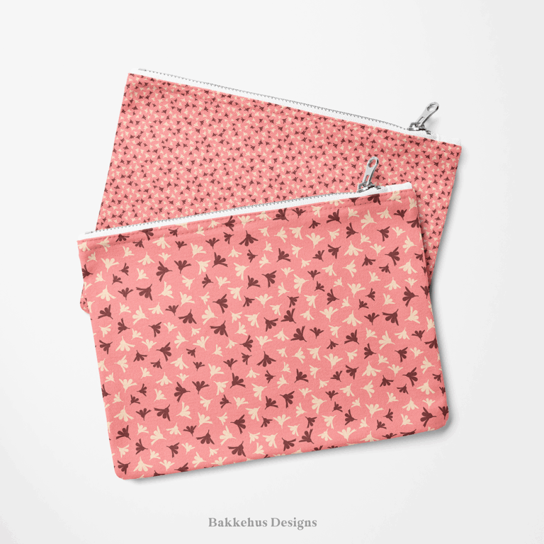Two zip pouches made from Ditsy Flower Sprigs fabric, one lying on the other, printed with tiny rosewood and cream flower sprigs on soft pink.