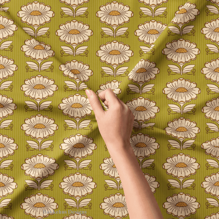 Close-up of a hand lifting Hillside Bloom fabric, showing the cream daisies, dotted mustard centres, brown outlines and the fine pinstripe on the olive green background.
