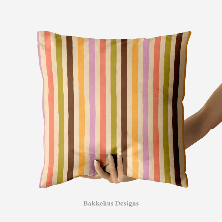 A hand holds up a square cushion printed with Organic Narrow Stripe, a hand drawn vertical stripe in earthy retro colours on cream.