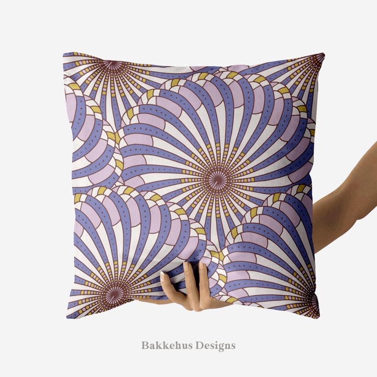 A hand holds up a square cushion printed with Retro Gatsby Disco, a large-scale Art Deco scallop fan pattern in cornflower blue and lilac. Overlapping fans radiate from dark centres, with dotted bands on a cream ground.