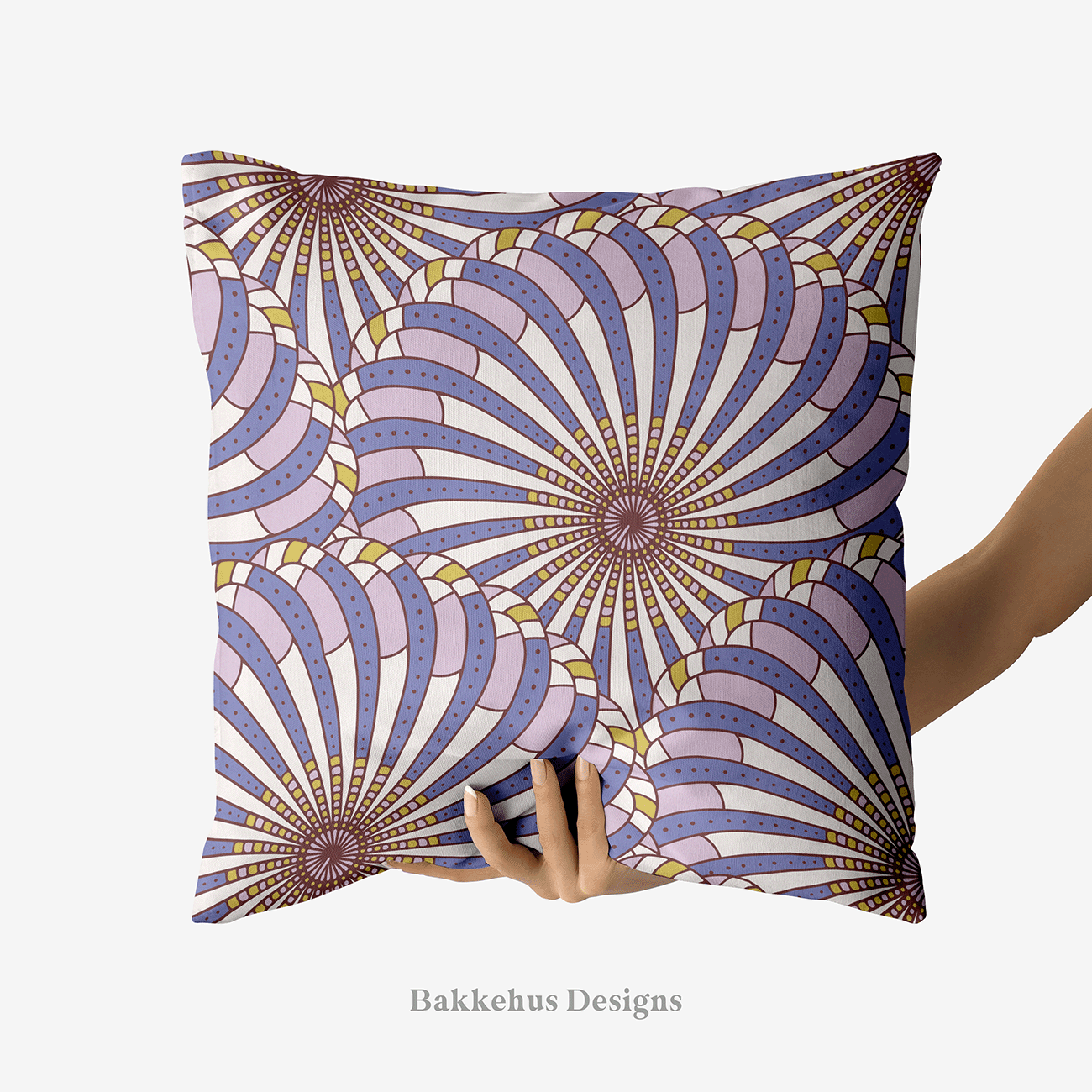 A hand holds up a square cushion printed with Retro Gatsby Disco, a large-scale Art Deco scallop fan pattern in cornflower blue and lilac. Overlapping fans radiate from dark centres, with dotted bands on a cream ground.