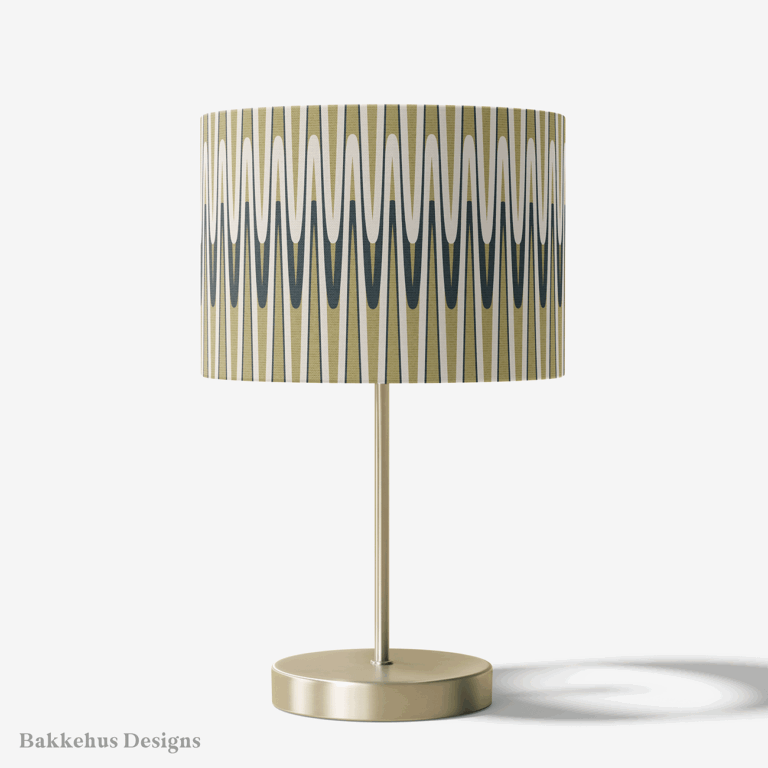 Table lamp with a brass stand and a round drum shade covered in the Retro Wavy Stripe pattern, with olive green and charcoal waves on cream.