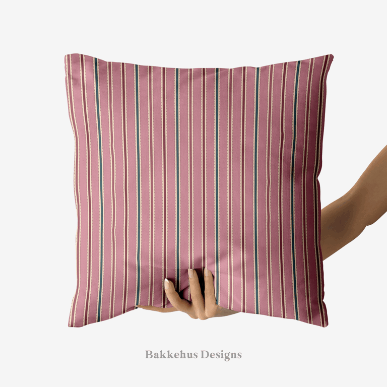 A hand holds up a square cushion printed with Scalloped Cabana Stripe, a vertical stripe in mauve, deep teal and burgundy edged with a cream scallop.