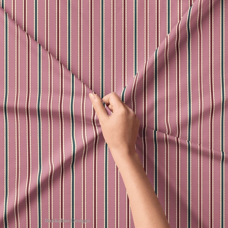 Close-up of a hand lifting Scalloped Cabana Stripe fabric, showing the hand drawn lines and cream scalloped edges between the mauve, deep teal and burgundy stripes.