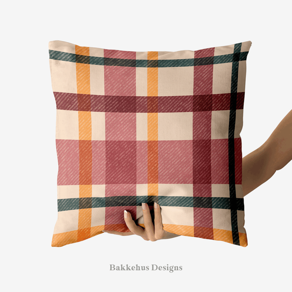 A hand holds up a square cushion printed with Textured Windowpane Plaid, large teal, burgundy, mauve and burnt orange windowpane checks on a warm beige background.