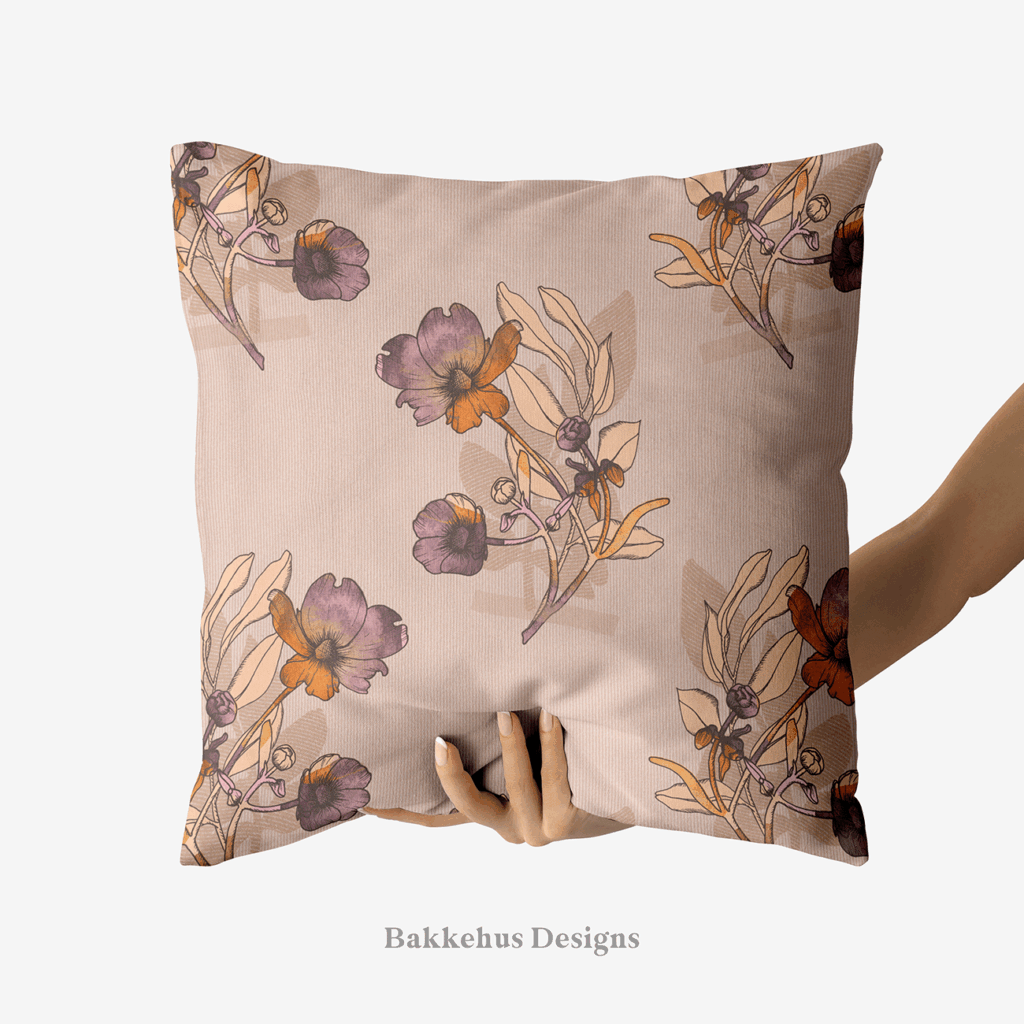 A hand holds up a square cushion printed with Vintage Buttercup Floral, hand-drawn ranunculus sprigs in mauve, plum and rust on a warm blush background.