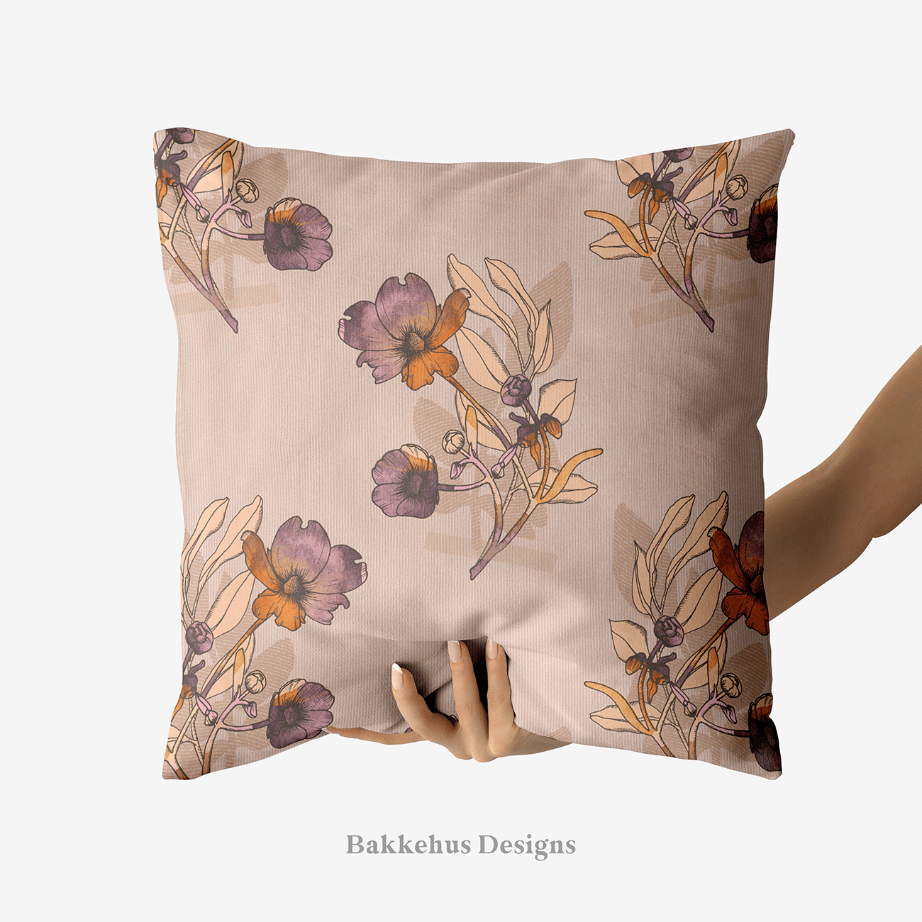 A hand holds up a square cushion printed with Vintage Buttercup Floral, hand-drawn ranunculus sprigs in mauve, plum and rust on a warm blush background.