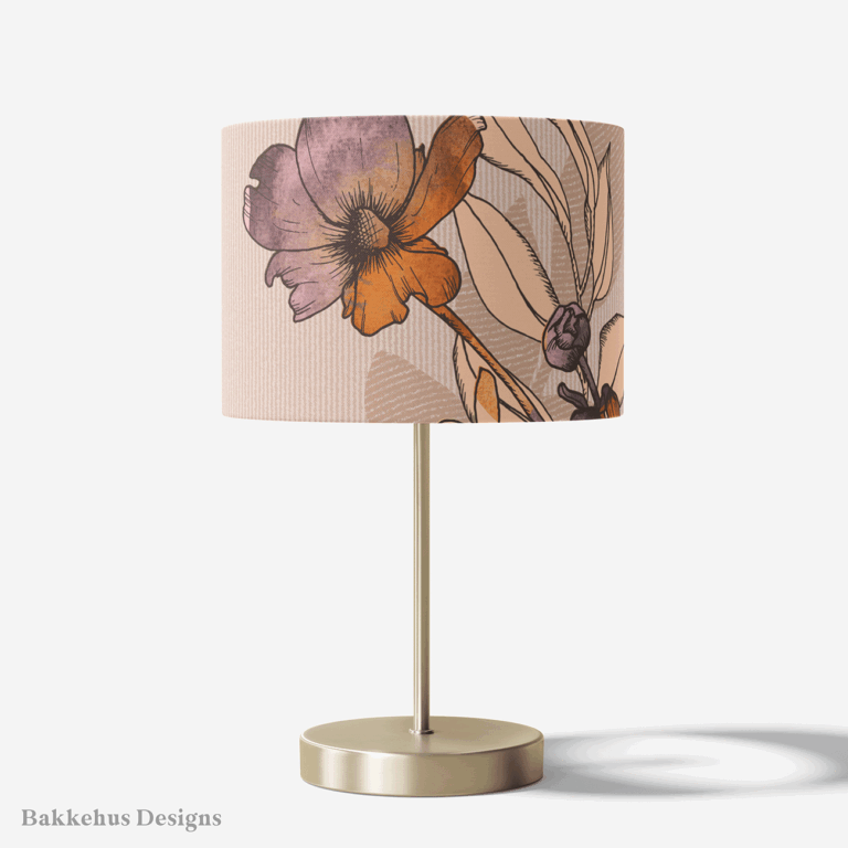 Table lamp with a brass stand and a round drum shade covered in Vintage Buttercup Floral, with large ranunculus flowers in mauve, plum and rust on blush.