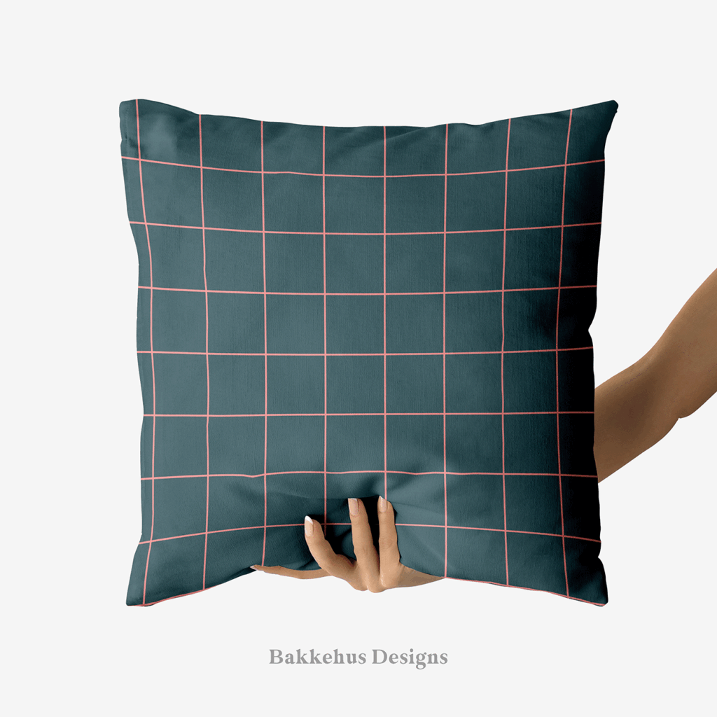 A hand holds up a square cushion printed with Windowpane Check, a simple grid of pink lines on deep teal.