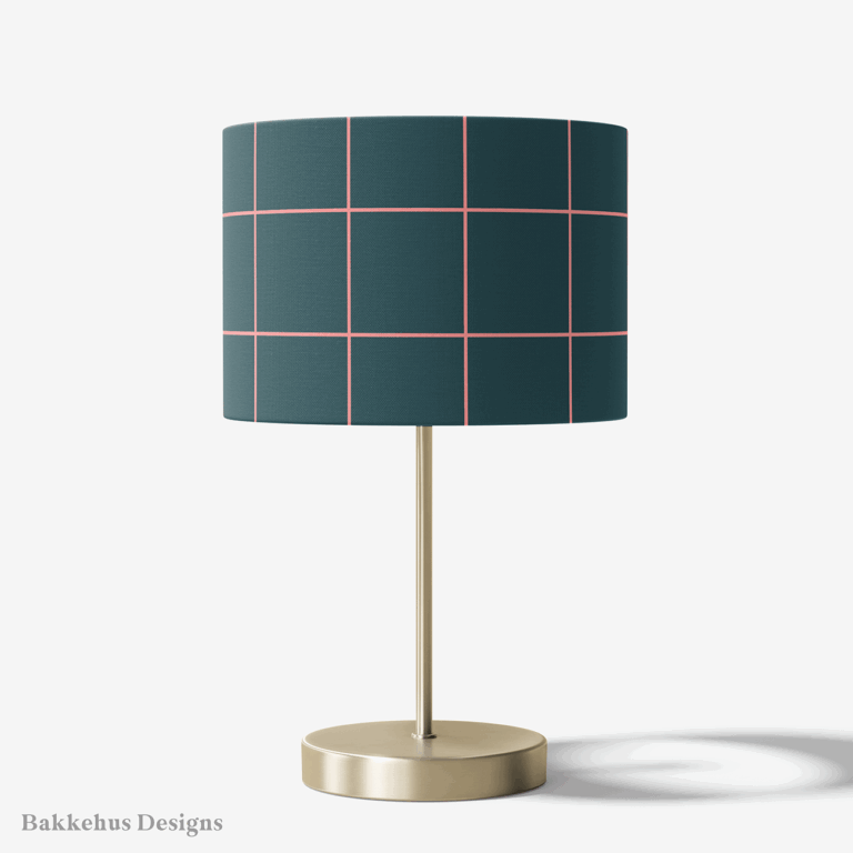 Table lamp with a brass stand and a round drum shade covered in Windowpane Check, a large pink grid on deep teal.